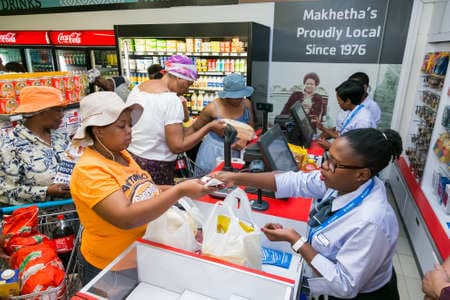 Soweto, South Africa - December 1, 2016: African cashier and customer at checkout at local Pick n Pay grocery store